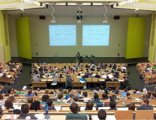 amphithéâtre universitaire avec étudiants et projecteurs affichant des formules mathématiques