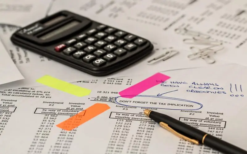 gestionnaire de paie analysant des documents financiers avec calculatrice et surligneurs colorés
