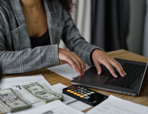 A businesswoman working on finance management with cash and calculator on desk.