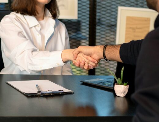 a man and a woman shaking hands in front of a laptop